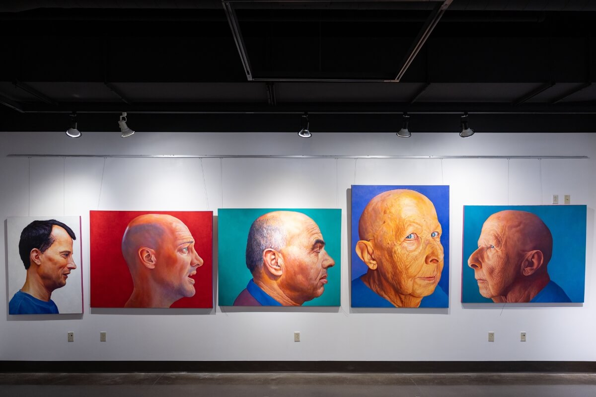 Photo of Carl Gombert art exhibit pieces hanging on a wall