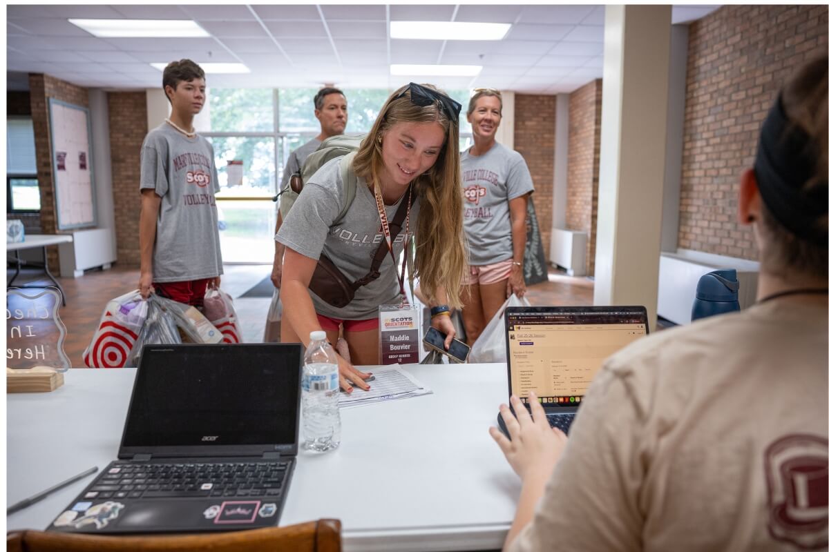 Photo of a smiling girl checking into her residence hall