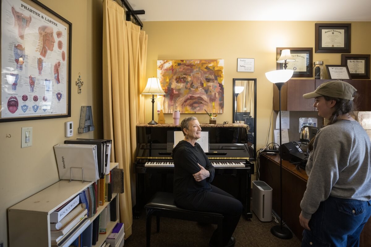 Photo of Alicia Massie-Legg seated at her piano, turned to talk to Dana Patterson '26.