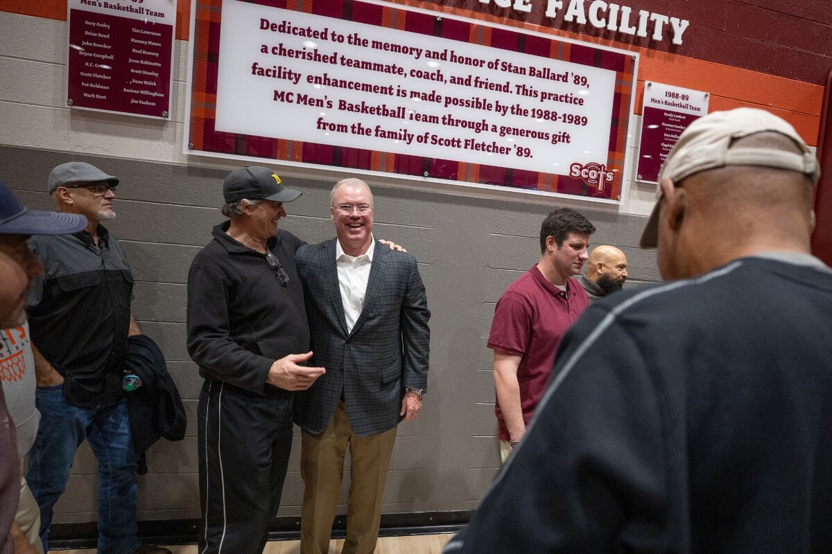 Photo of friends and supporters beneath the Ballard Practice Facility sign