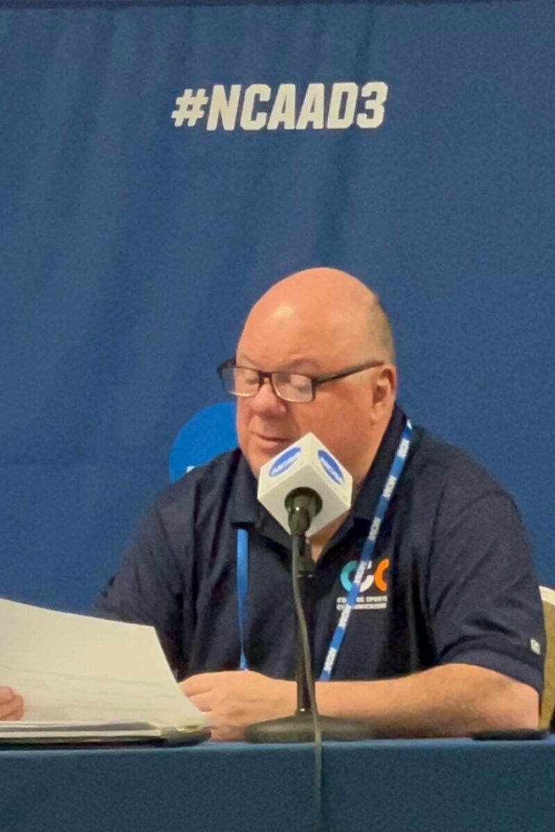 Photo of John Painter reading stats at a press conference