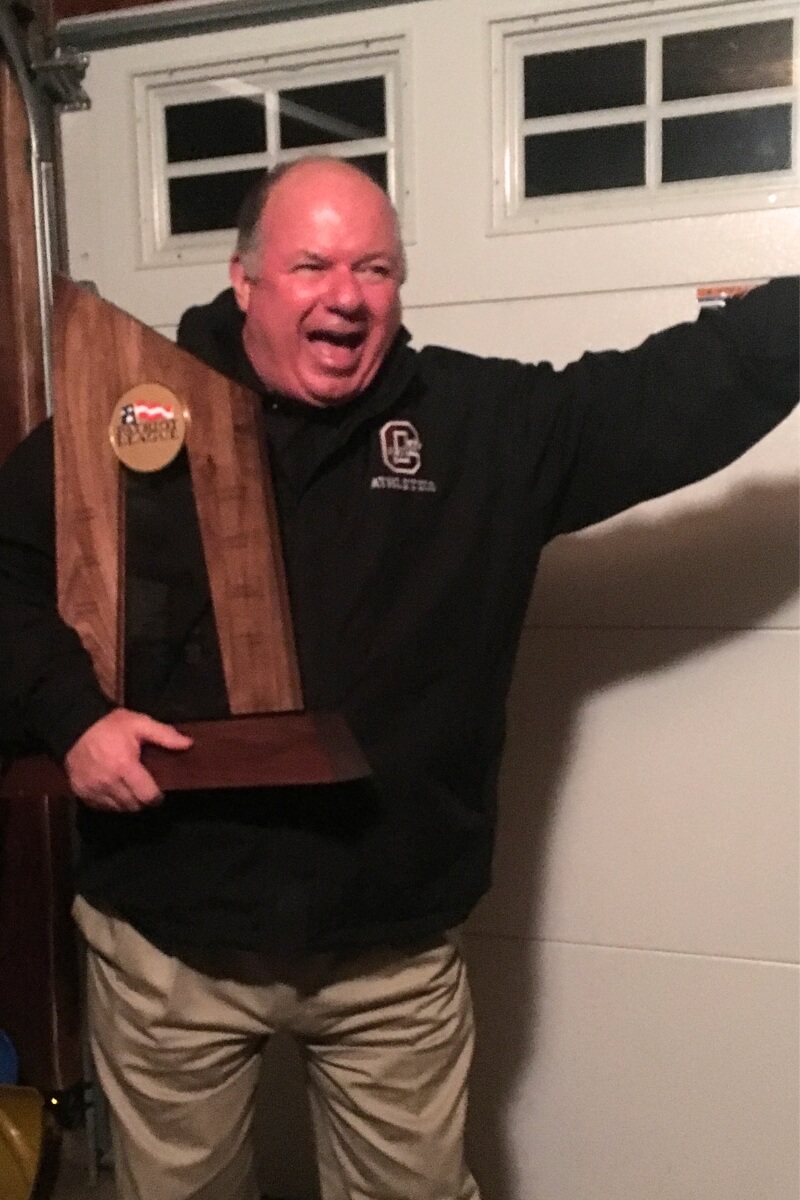 Photo of John Painter holding a trophy and gesticulating excitedly