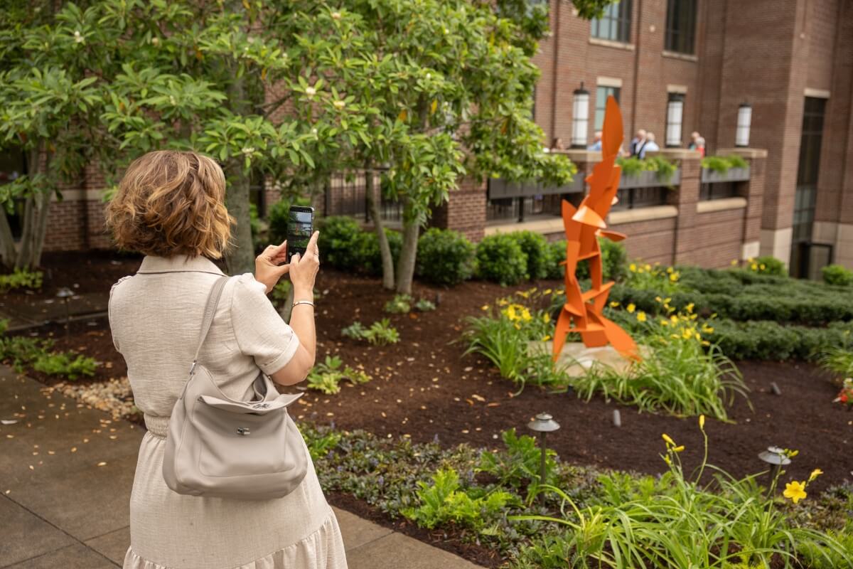 Photo of a gala attendee taking a photo of the treble clef sculpture in the Clayton Center memorial garden