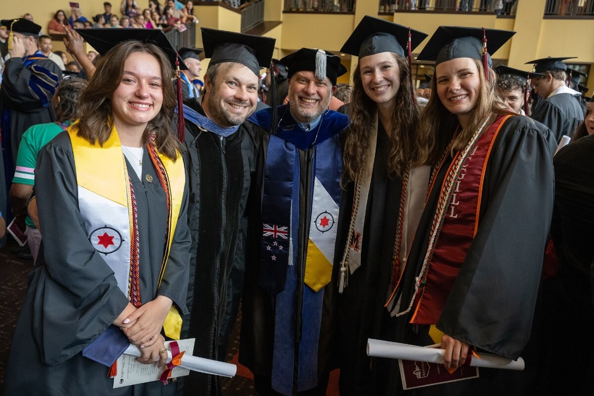Photo of two professors and three graduates smiling in their regalia after the Maryville College Commencement ceremony on May 3, 2025.
