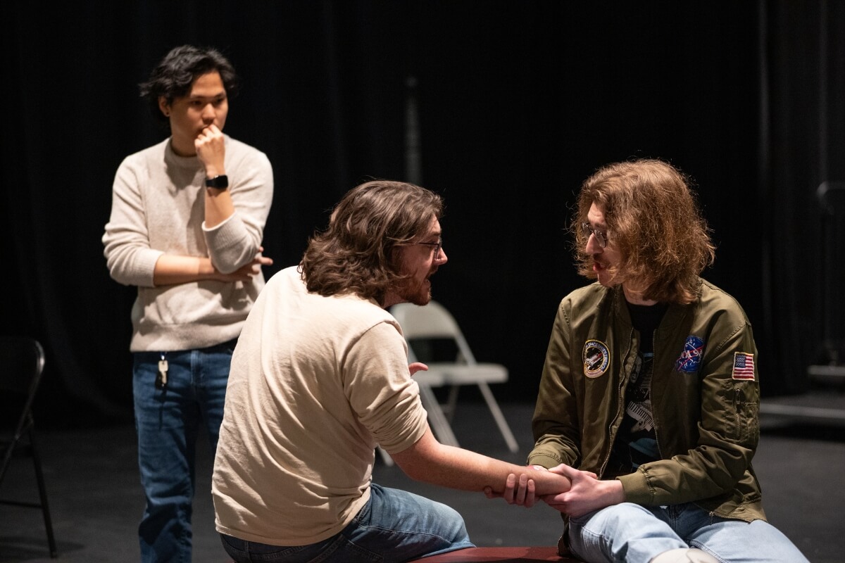 Photo of Andrew Hastings '25 observing a scene from "Angels in America" with two of his stars