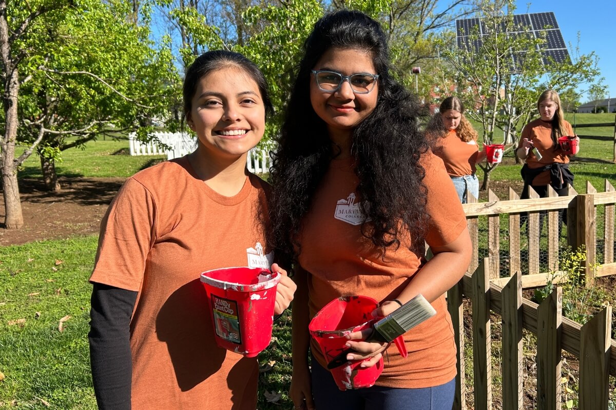 Photo of two Maryville College students smiling and holding paint brushes during KT Weekend 2024 events