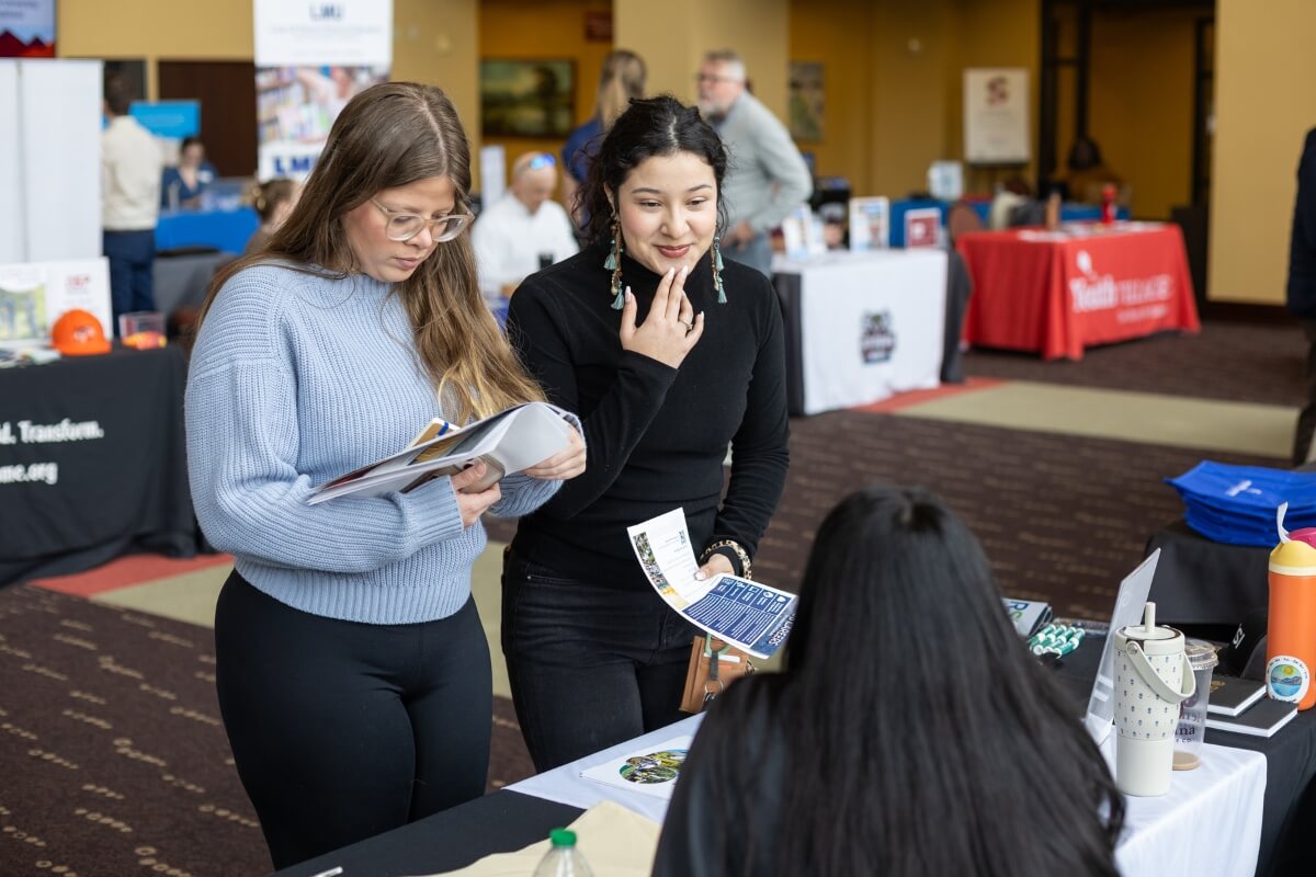 Photo of two MC students gathering information at a table at the Maryville College Spring Opportunities Fair.