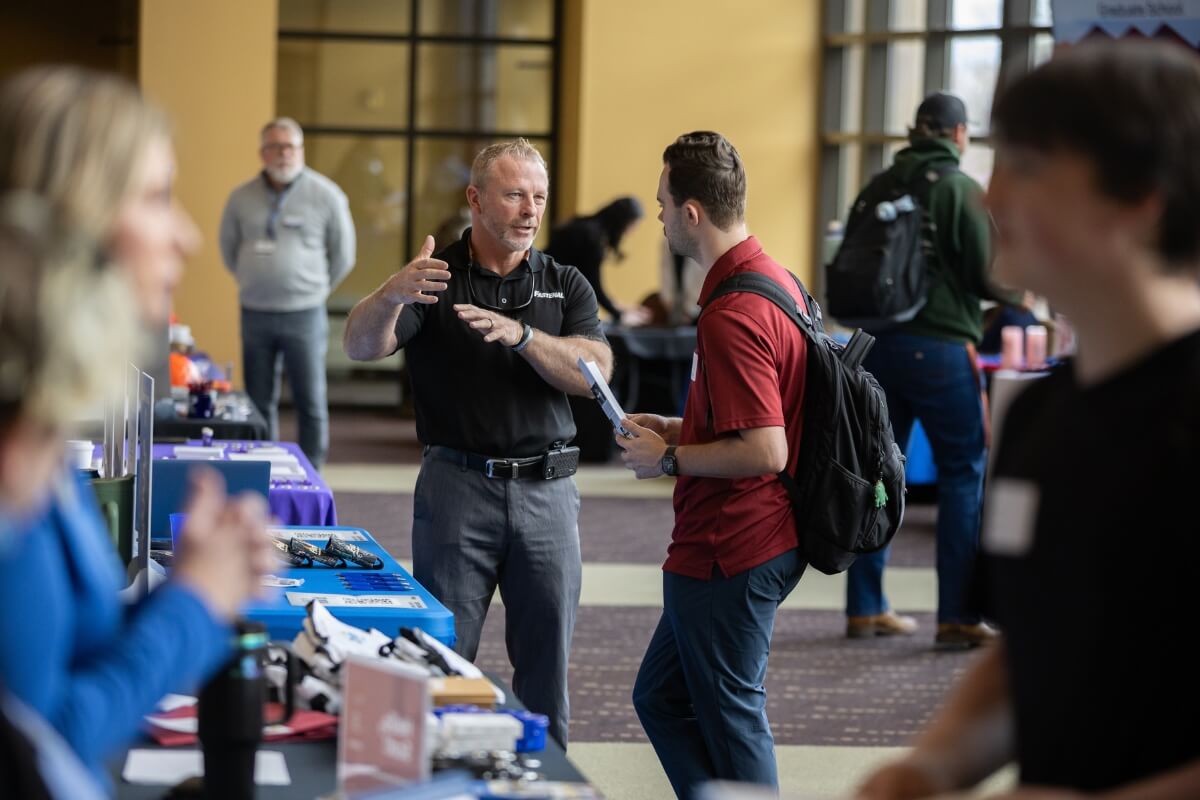 Photo of a vendor at Maryville College Spring Opportunities Fair talking to a student