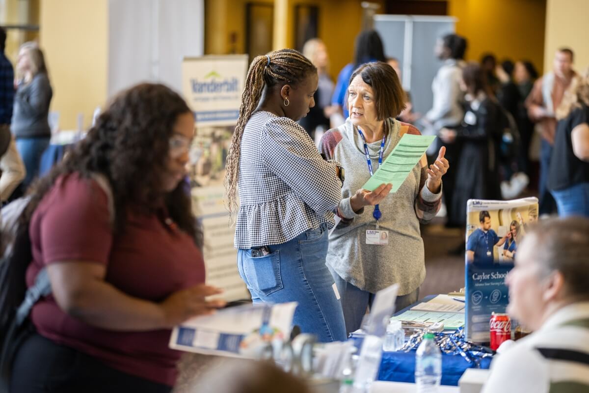 Photo of a vendor talking to a Maryville College student at the MC Career Center spring fair