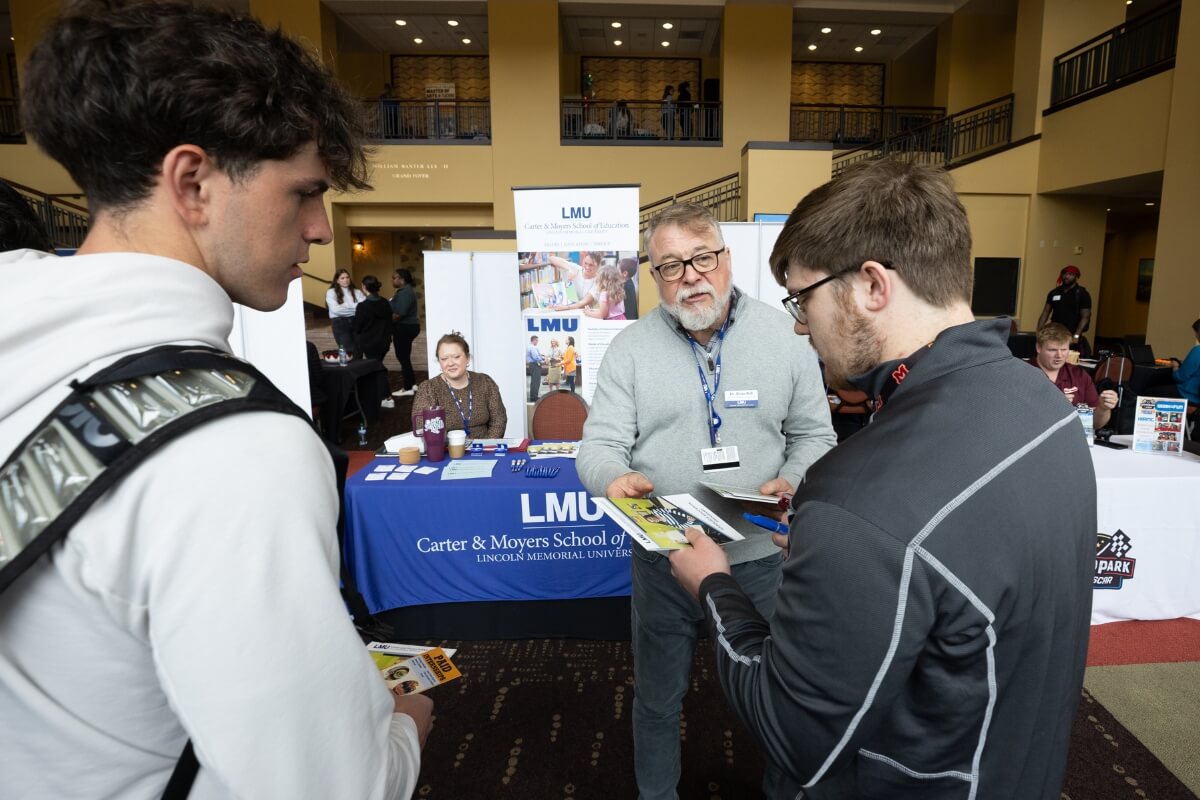 Photo of two Maryville College students flanking a representative from Lincoln Memorial University at the Maryville College Spring Opportunities Fair