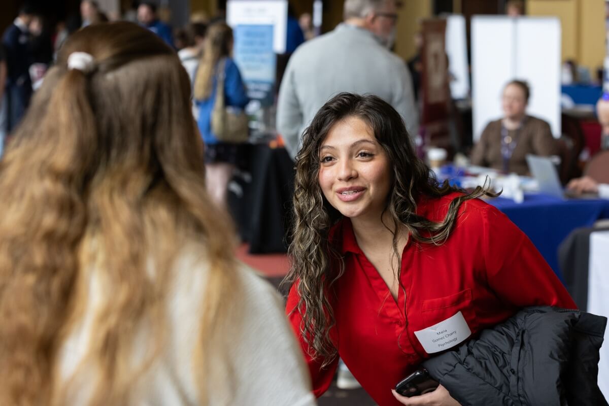 Photo of a student leaning over a table to talk to a vendor