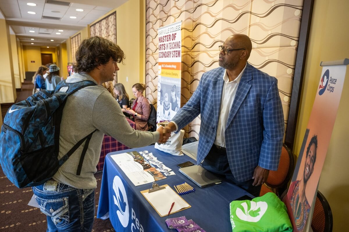 Photo of a Maryville College student shaking hands with a Peace Corps volunteer at the Maryville College Spring Opportunities Fair