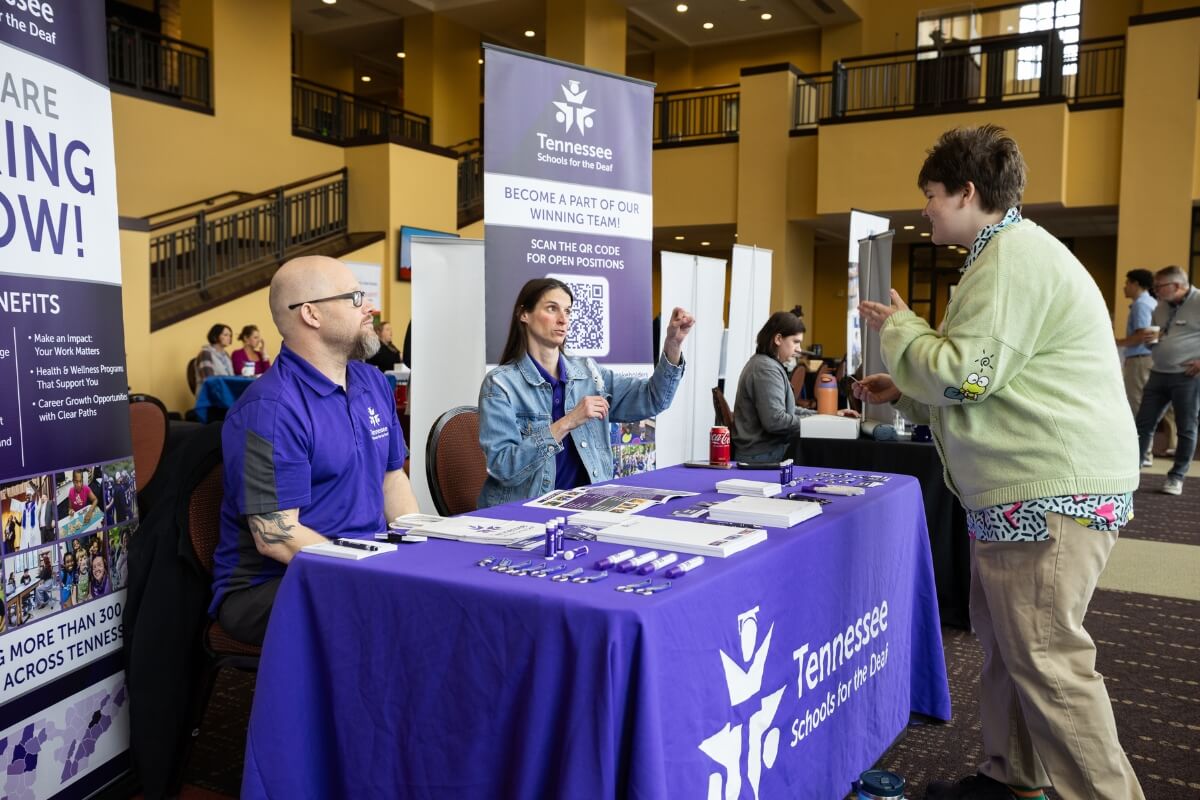 Photo of a student talking with representatives from the Tennessee School for the Deaf at the Maryville College Spring Opportunities Fair