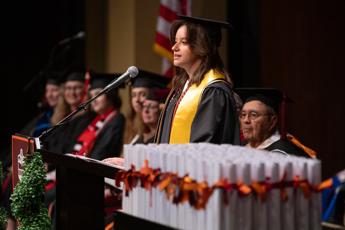 Photo of a senior speaking at a podium, on the verge of tears