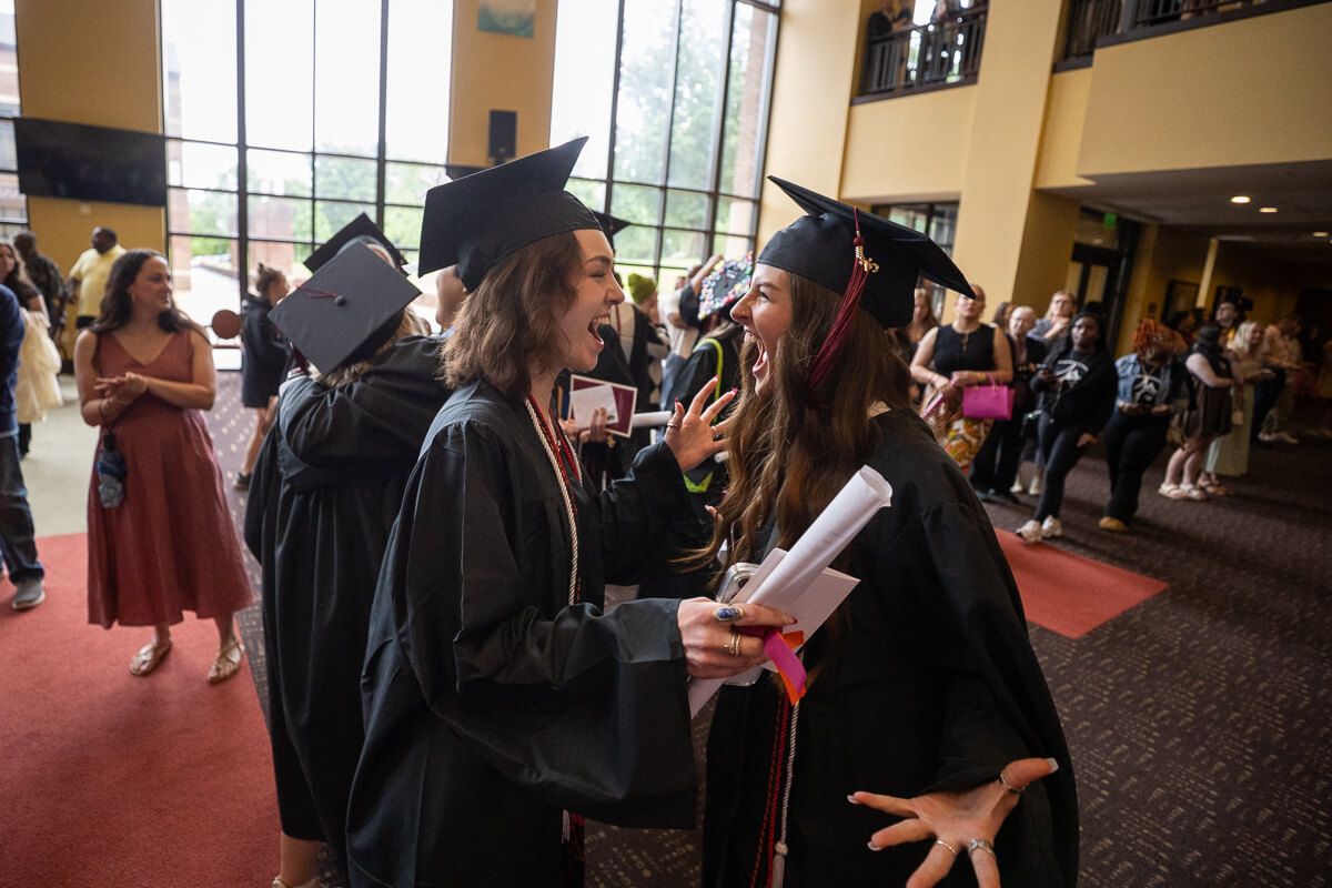 Photo of two Maryville College seniors squealing in delight after receiving their diplomas.