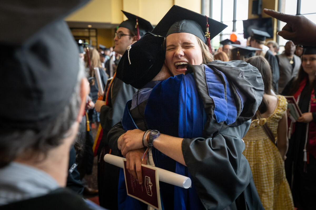 Photo of a faculty member hugging an emotional graduating senior