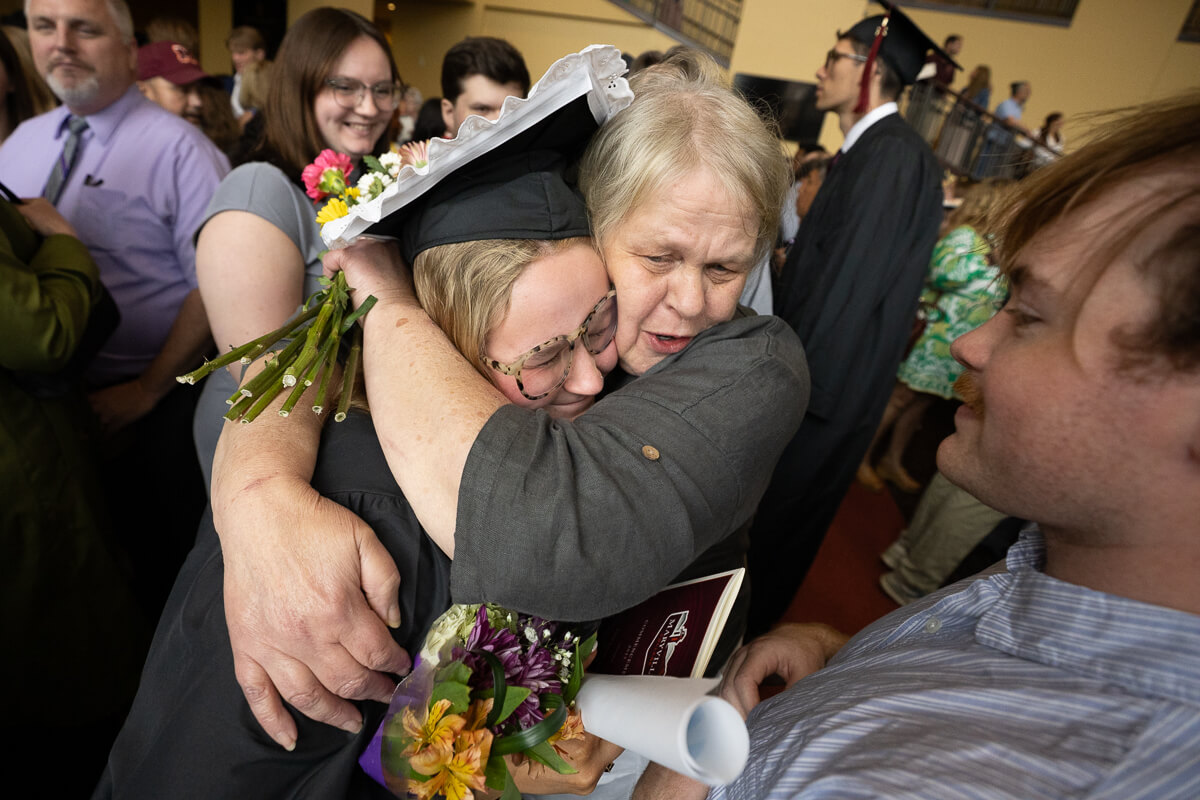 Photo of a family member hugging a graduate's neck with fierce pride
