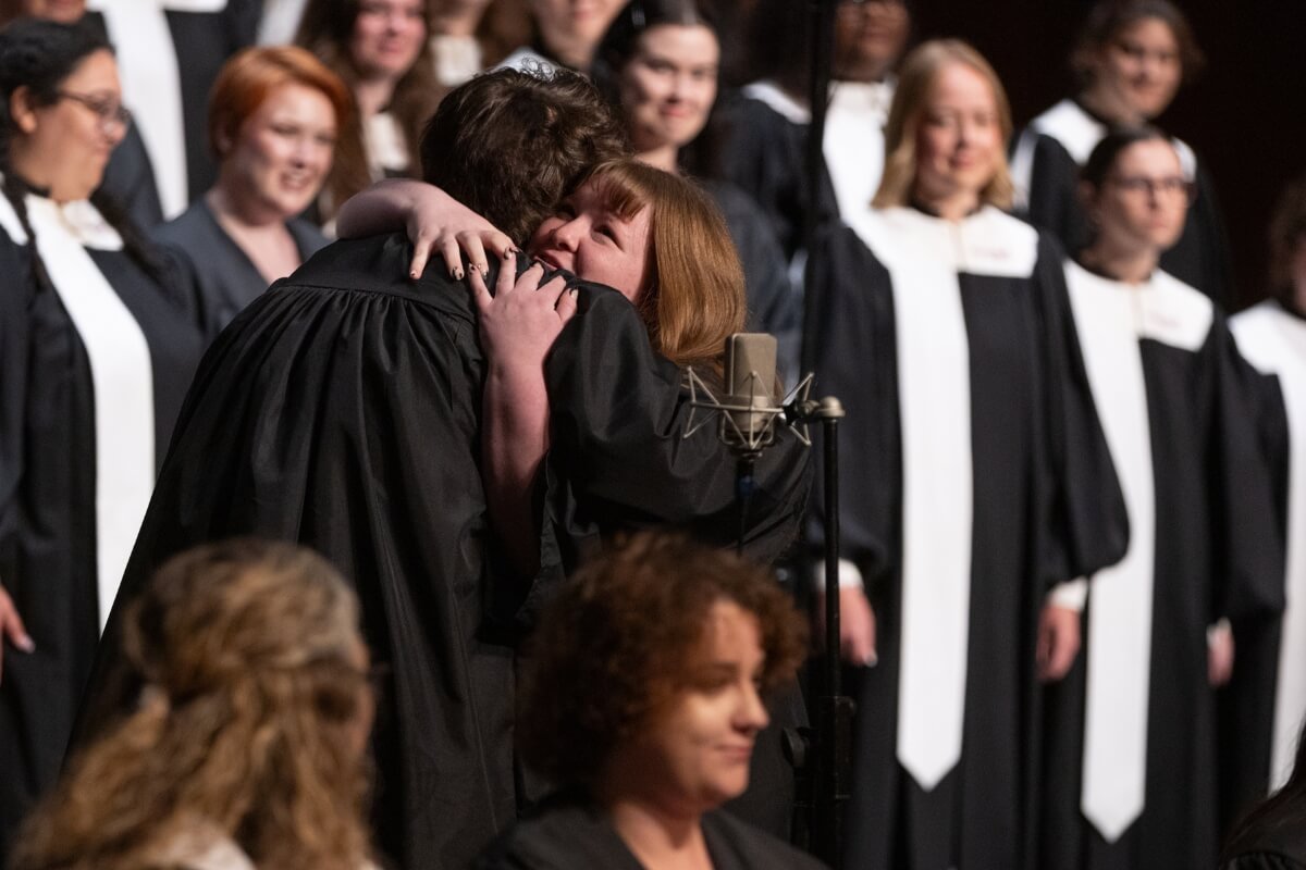 Photo of two MC Concert Choir members hugging one another