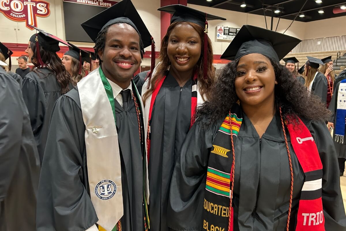 Photo of three smiling Black Maryville College students wearing caps and gowns