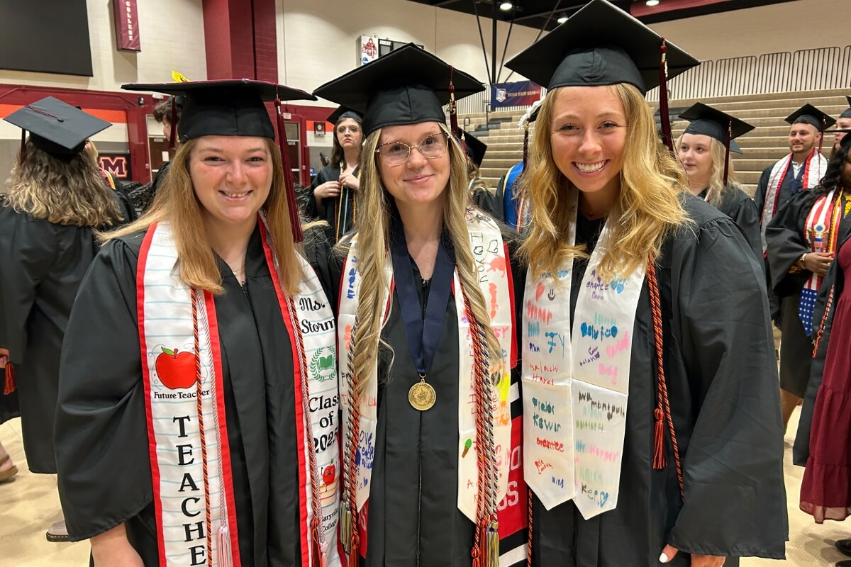 Photo of three smiling girls in their caps, gowns and stoles before Maryville College Commencement 2025 takes place