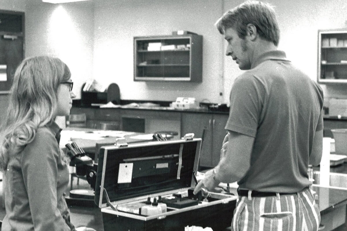 Black and white photo of a male professor in a science laboratory with a female student