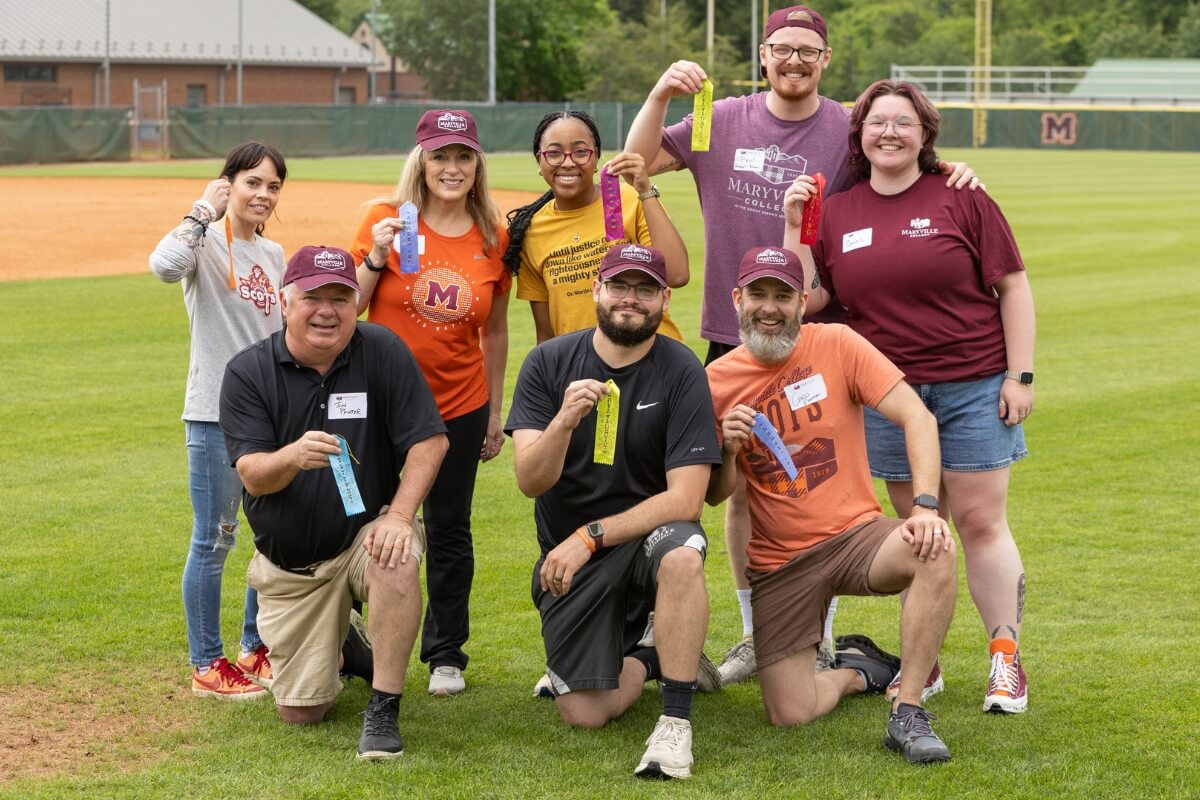 Photo of a team of staff members holding up award ribbons