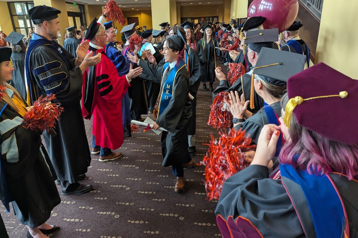 Photo of smiling student walking through a line of faculty members after the Maryville College Commencement 2025 ceremony