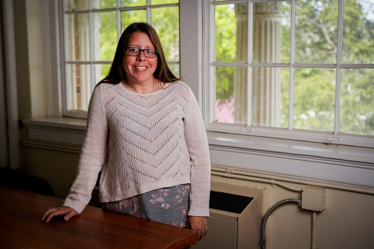 Photo of Late MC professor Dr Regina Benedict, standing at a table and smiling