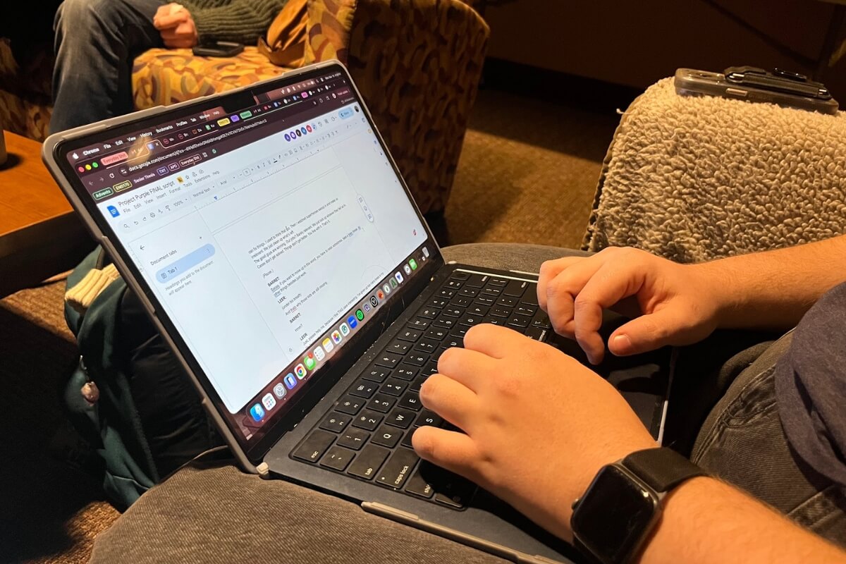 Close-up photo of a pair of hands (belonging to Maryville College student Kat Wilson '28) on a laptop keyboard with an "Advents" script on the screen