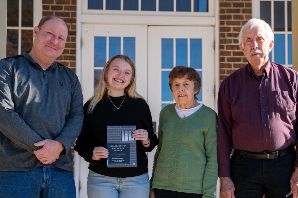 Photo of the widower and parents of Dr. Regina Benedict with a student who received the scholarship these family members established in Benedict's name
