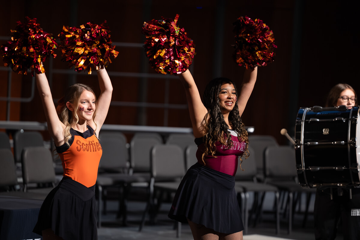 Photo of two members of the Maryville College Pom Squad on stage, arms raised and holding pom-poms.