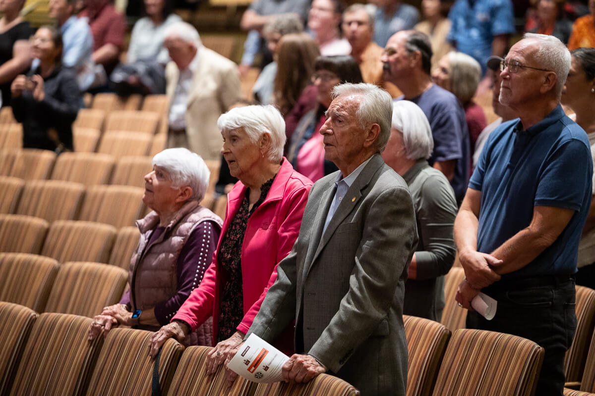 Photo of people in an auditorium standing and staring ahead