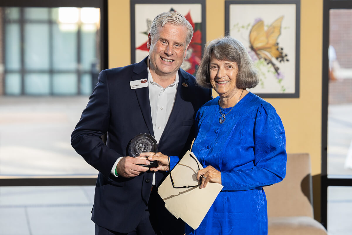 Photo of Mary Boldon with President Bryan Coker in front of a window