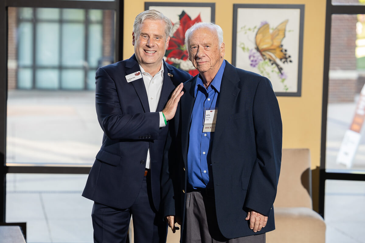 Photo of MC President Bryan Coker smiling with his hand on a donor's chest standing beside him