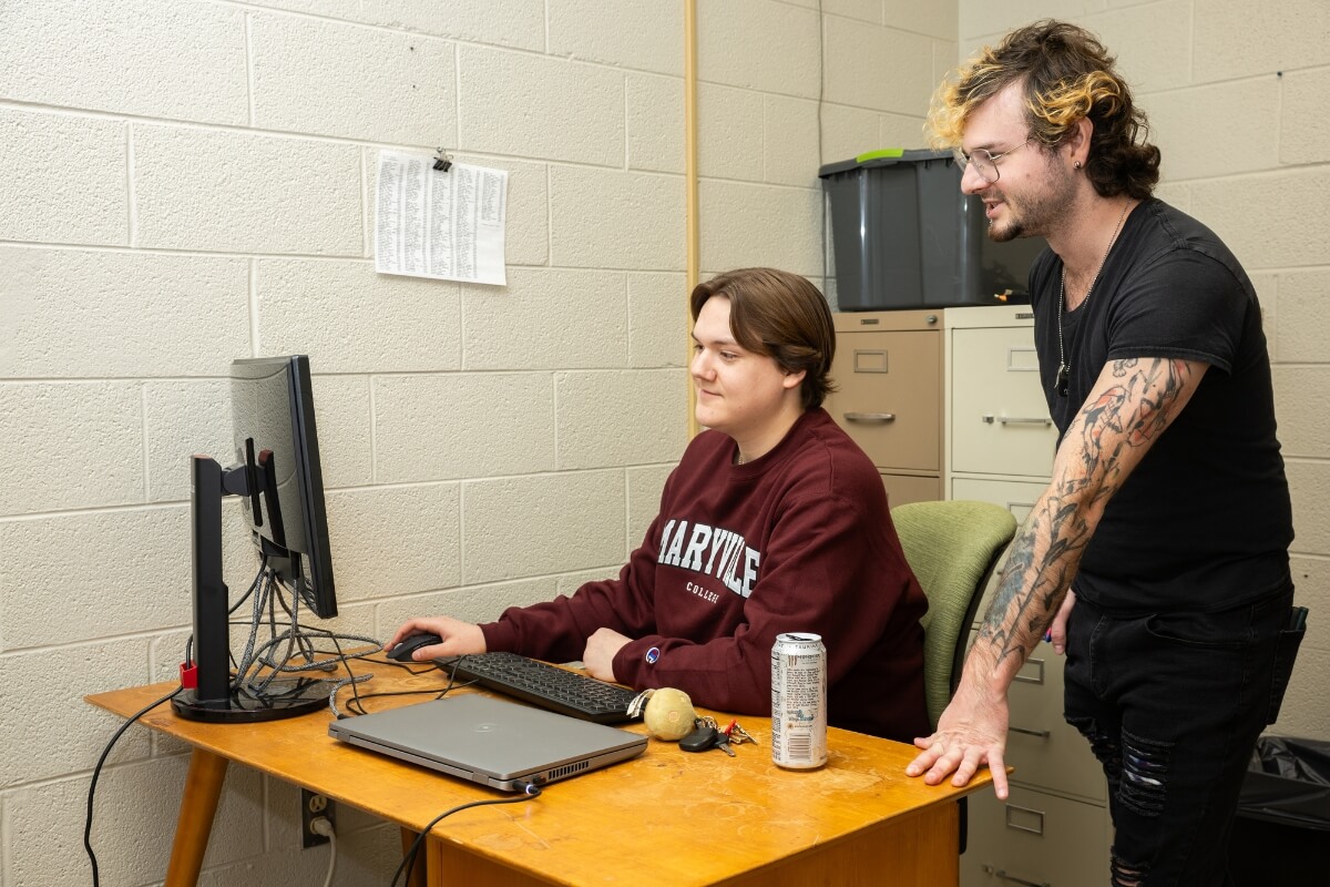Photo of Dr. Jeff Kelly looking over the shoulder of student Clayton Tuggle, who works on a computer