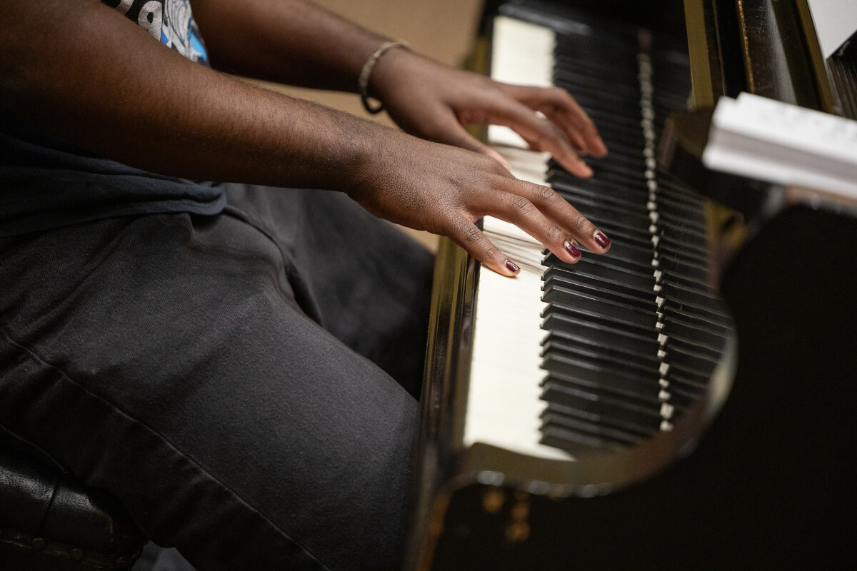 Photo of a Black Maryville College student's forearms and hands on the keys of a piano