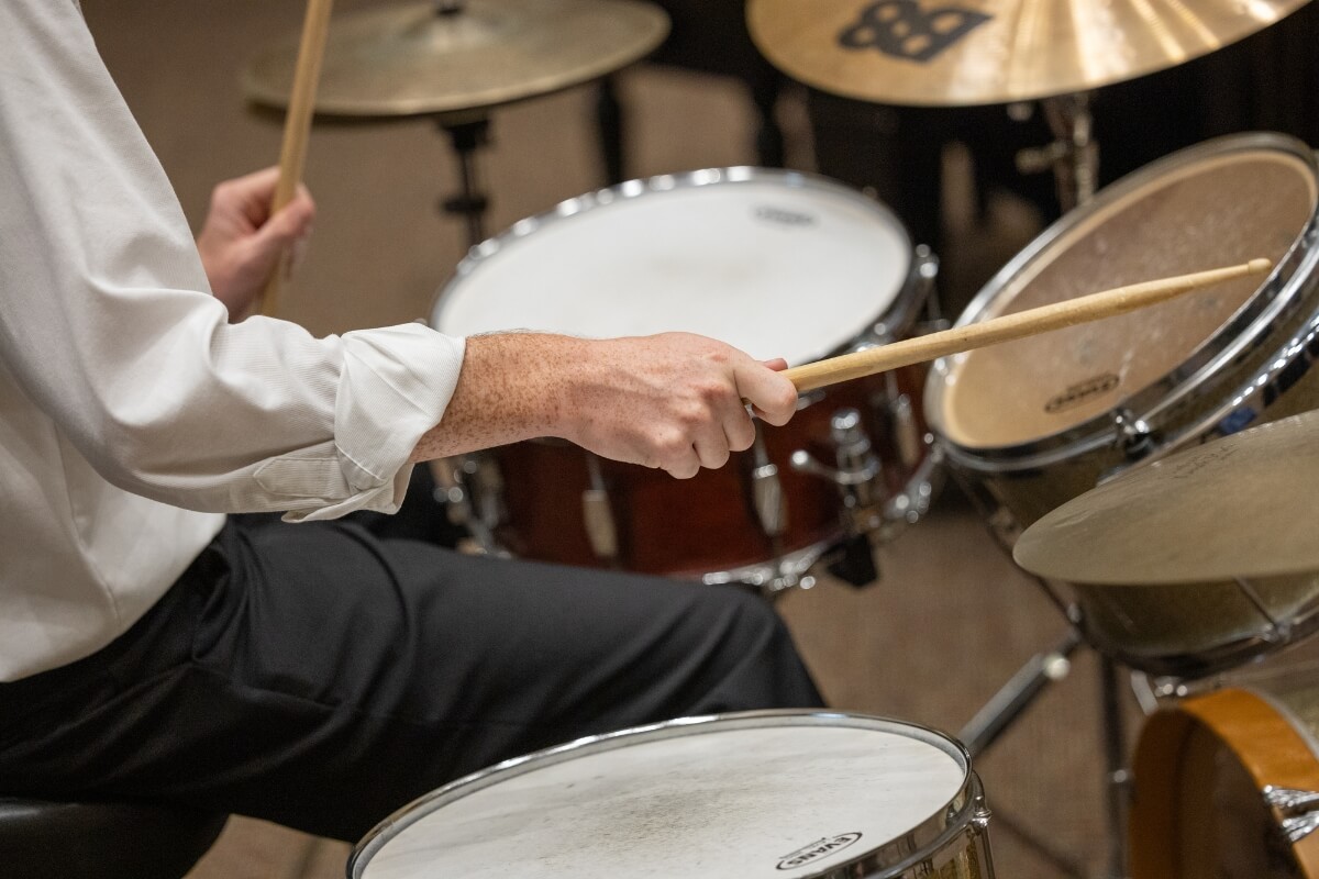 Photo of a young man with sleeves rolled up playing the drums