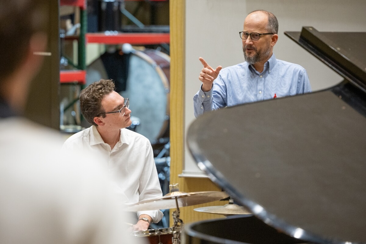 Photo of Dr. Bill Swann, standing, and Michael Howard '28, seated at the drumkit
