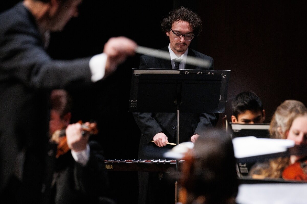 Photo of a member of the Orchestra at Maryville College performing with Conductor Dr. Ace Edewards directing in the foreground
