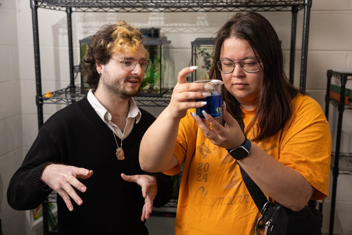 Photo of Dr. Jeff Kelly talking to student Sam Sasinouski, who examines a container holding zebrafish