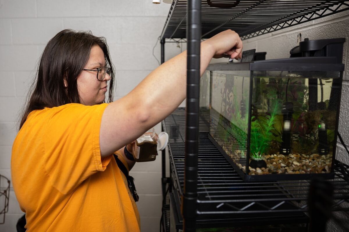 Photo of Sami Sasinouski, one of two Maryville College Ledford Scholars, feeding fish