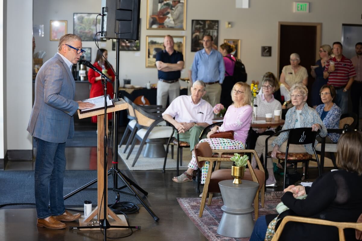 Photo of a crowd of people inside the Vienna Coffee space on the MC campus listening to Dr. Bryan Coker
