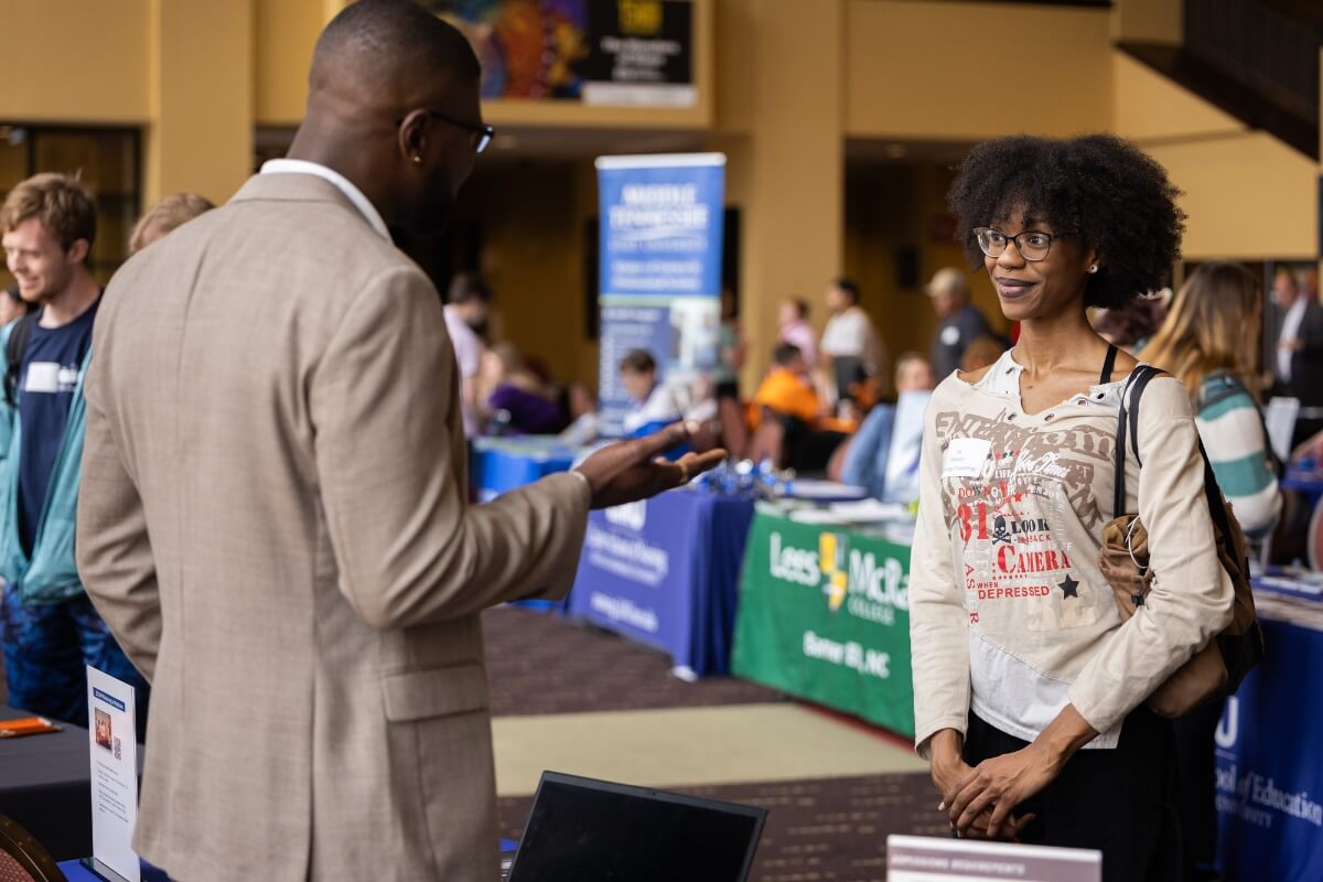 Photo of a smiling Black girl talking to a Black man