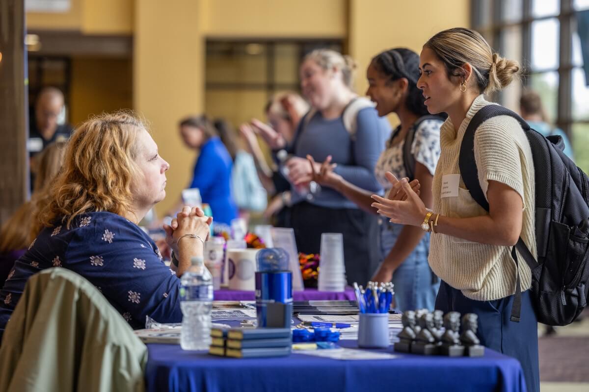 Photo of a seated woman listening intently to a student talking