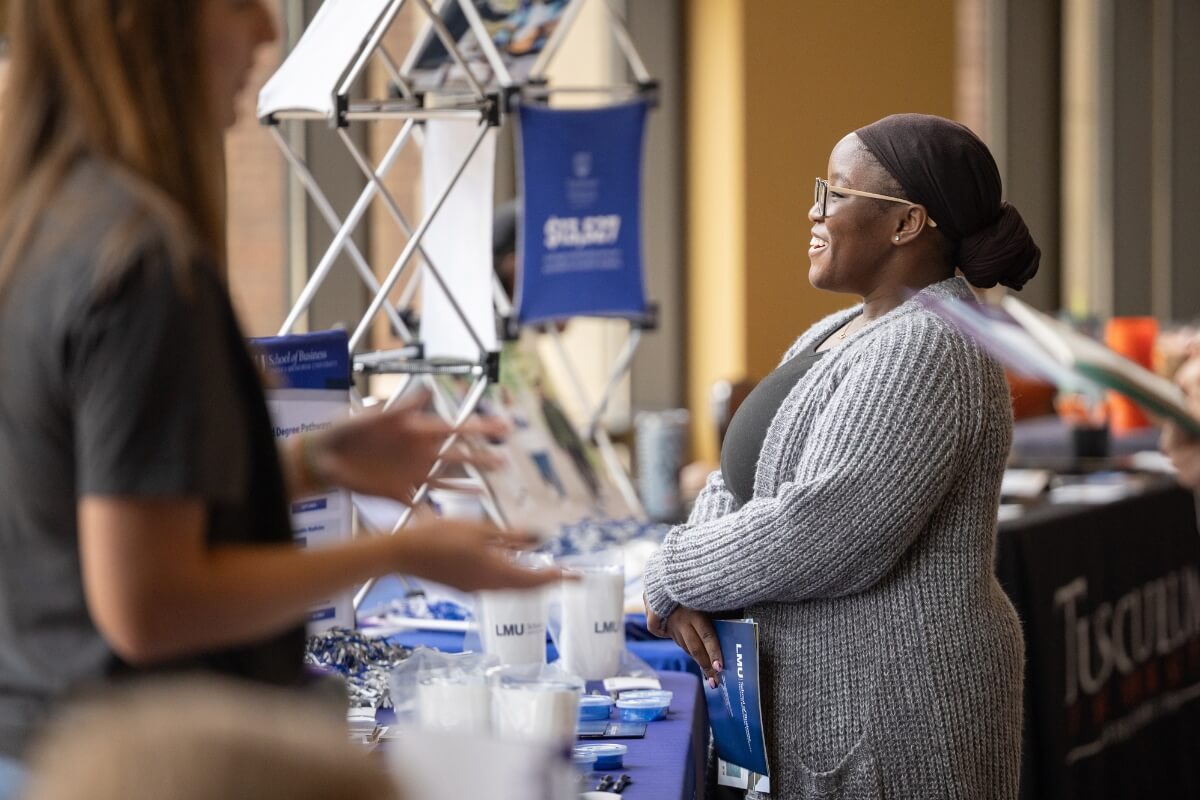 Photo of a Black woman smiling and listening intently at someone off camera