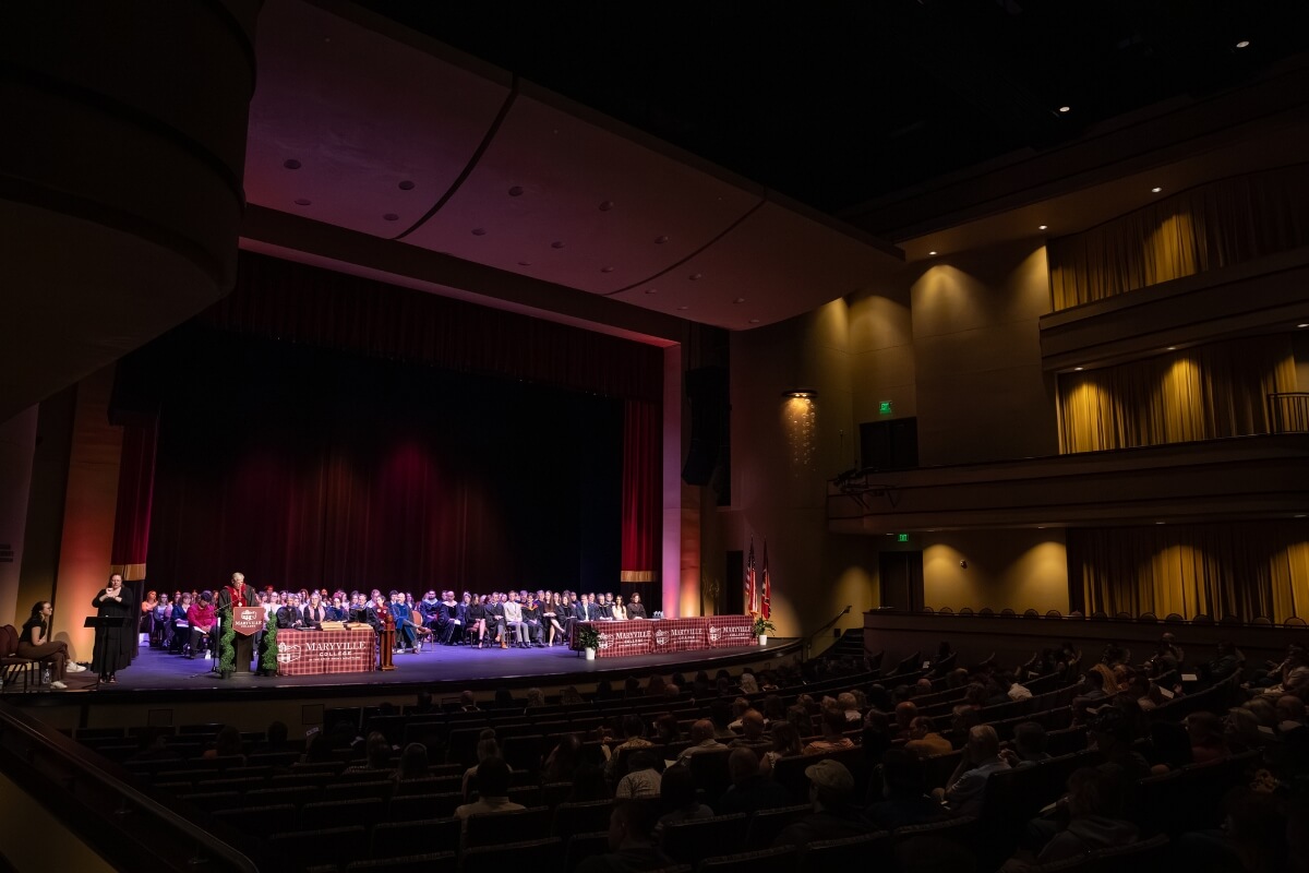 Photo of an auditorium filled with people under low lighting
