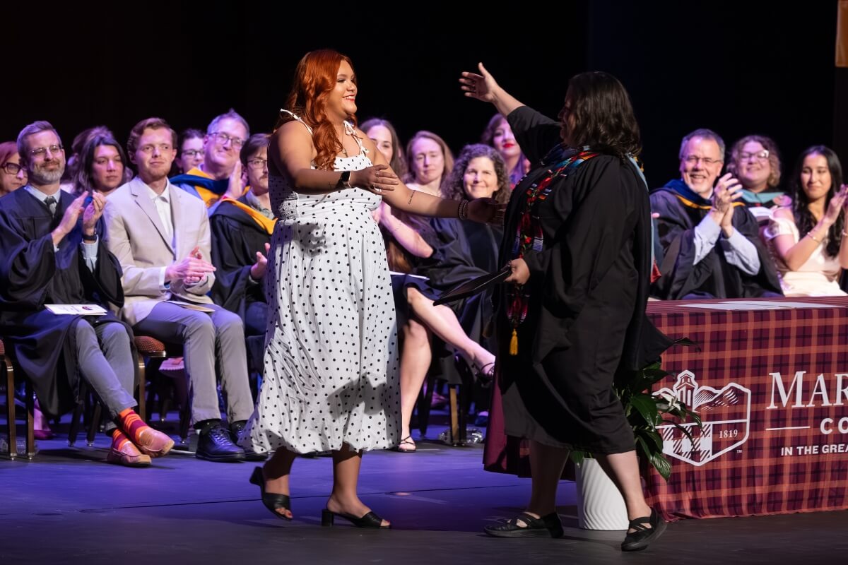 Photo of a girl going in for a hug from a woman giving her an award