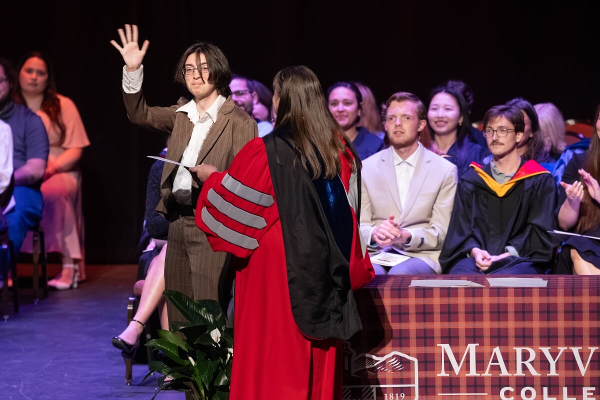 Photo of a student waving to a crowd after getting an award