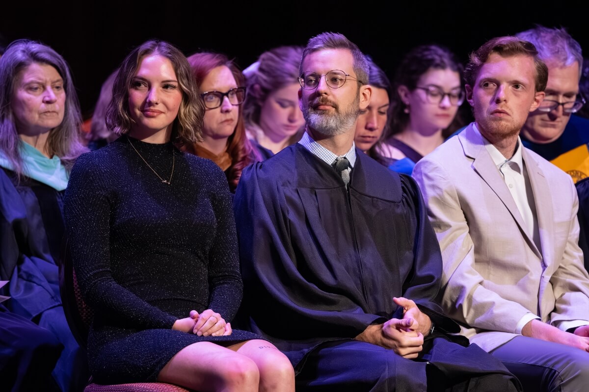 Photo of students and faculty members seated and staring at the podium