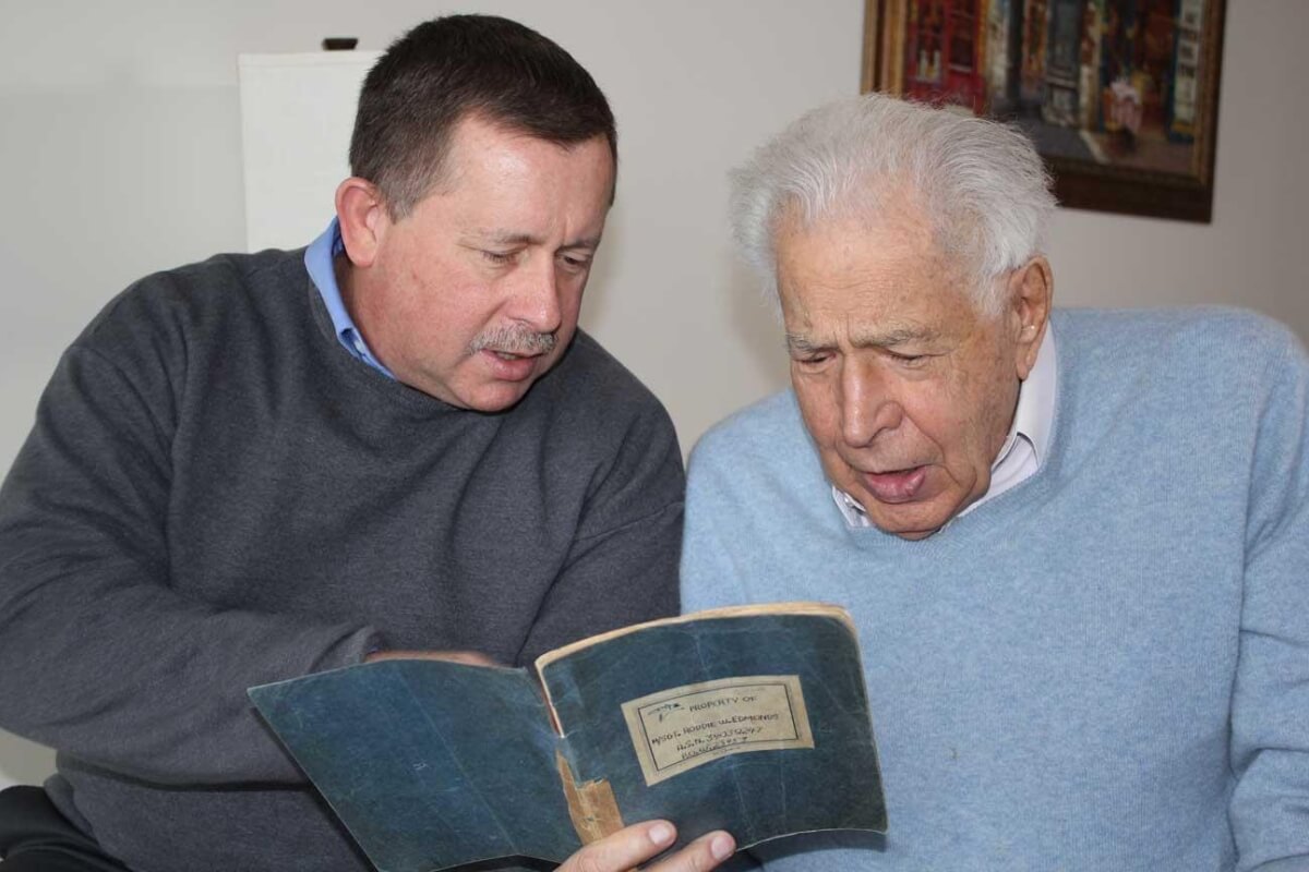 Photo of Chris Edmonds looking through a journal with Lester Tanner